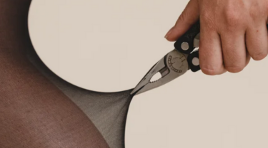 A person wearing SRTX tights using long nose pliers to pull on tights demonstrating the products strength.