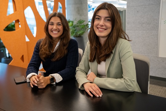 Two EDC employees sitting at a desk smiling at the camera. 