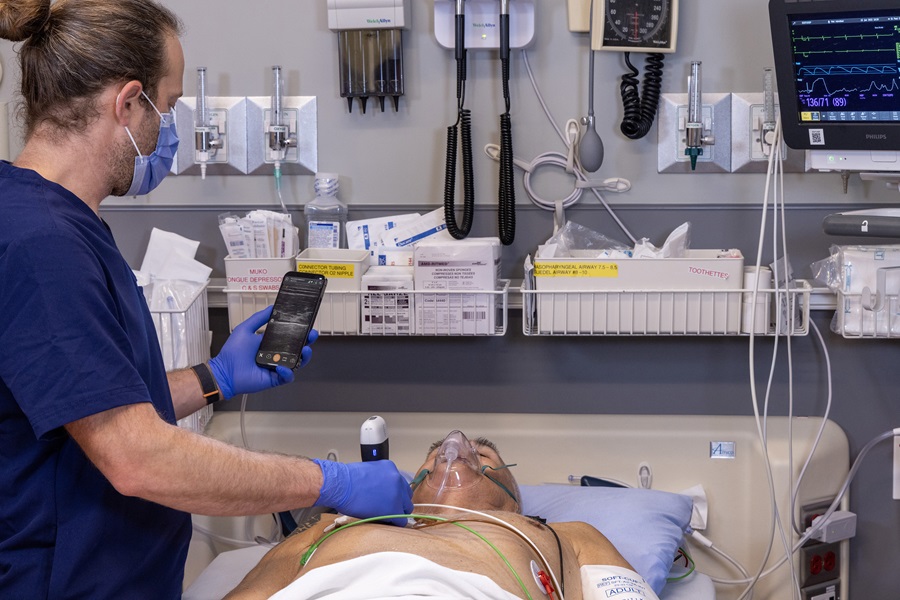 medical staff using Clarius ultrasound device to check patient lungs in hospital.