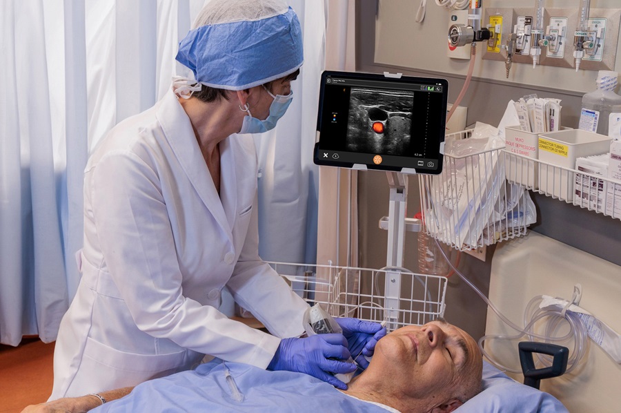 doctor using ultrasound device with image projected on tablet to perform procedure on patient neck