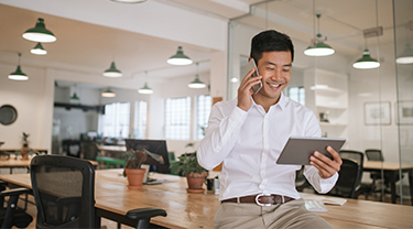 Businessman talking to an export advisor on the phone and looking at company information on his tablet