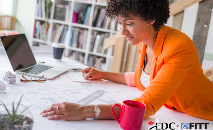Woman writing on a notepad while working at her desk with a laptop.