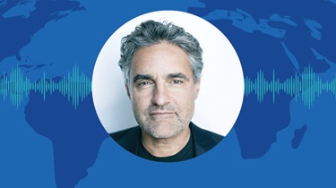 Joe Mimran poses confidently arms crossed infront of sound waves