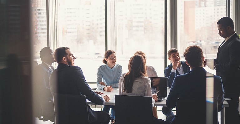 Employees collaborating at a board room table to be more competitive globally