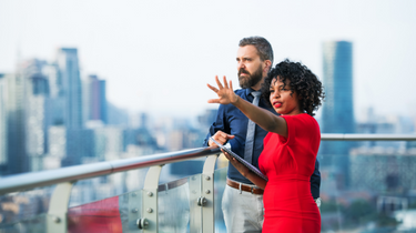 Two individuals talking outside and looking at the horizon.