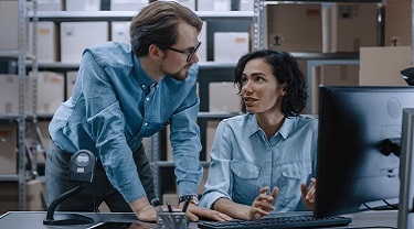 Two colleagues consult with each other in a warehouse.